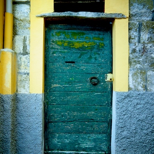 Porte en bois verte avec anneau surmonté d'une pierre sur un mur jaune et vert - France  - collection de photos clin d'oeil, catégorie portes